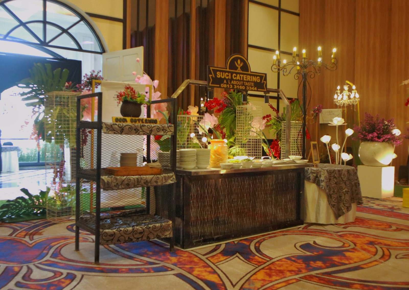 Gubukan Suci Catering dengan rangka besi dan hiasan bunga di sudut gedung