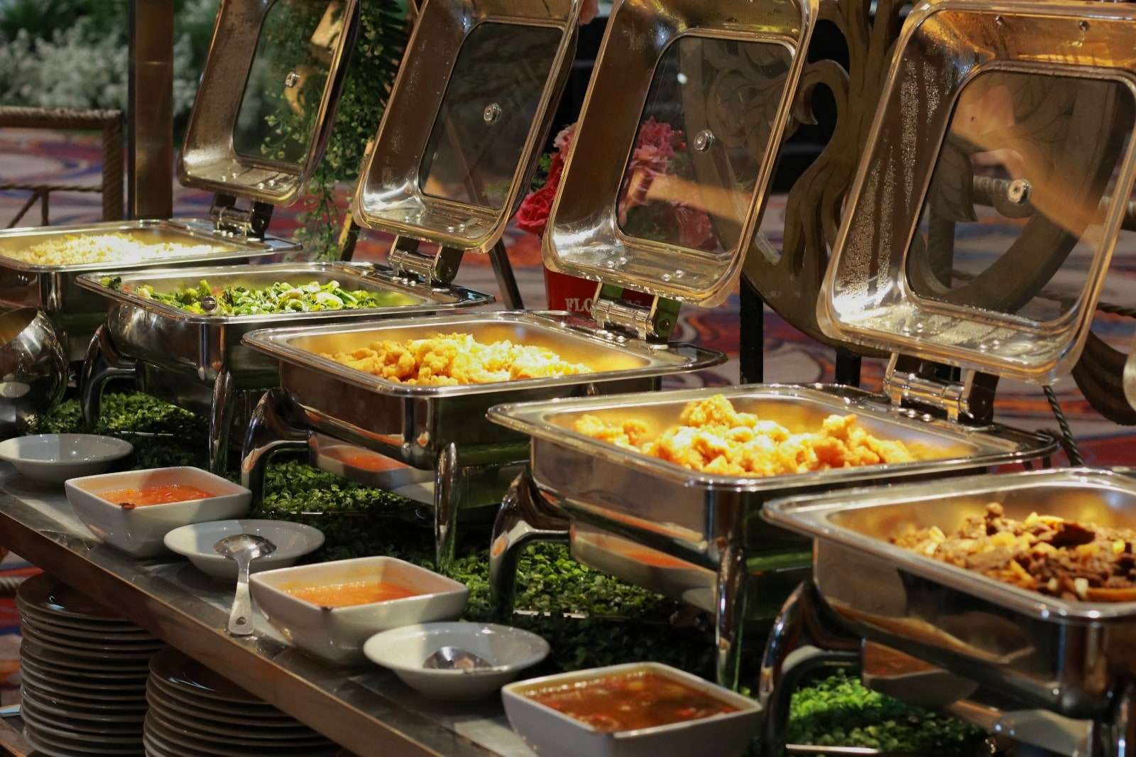 Deretan pemanas saji berisi lauk prasmanan dan mangkuk saus di meja Suci Catering