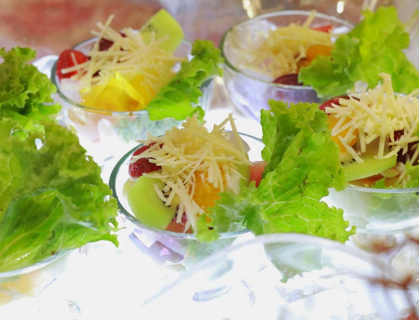 Salad buah dengan parutan keju dan daun selada di gelas saji